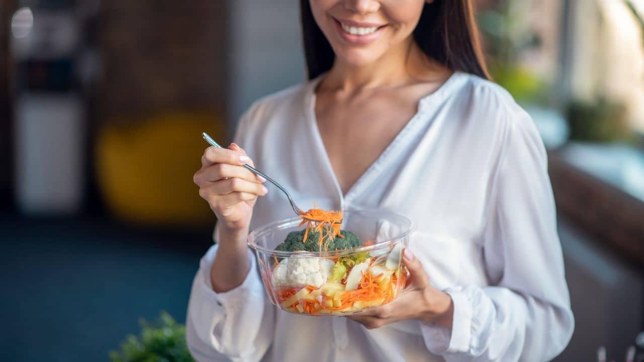 Woman smiling, eating the food to help you avoid gaining weight